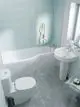 Badezimmeransicht mit hellblauen Wandfliesen, einer Badewanne, einem WC und einem Waschbecken. Ideal Standard Armatur an Waschbecken montiert, schlichtes Design.